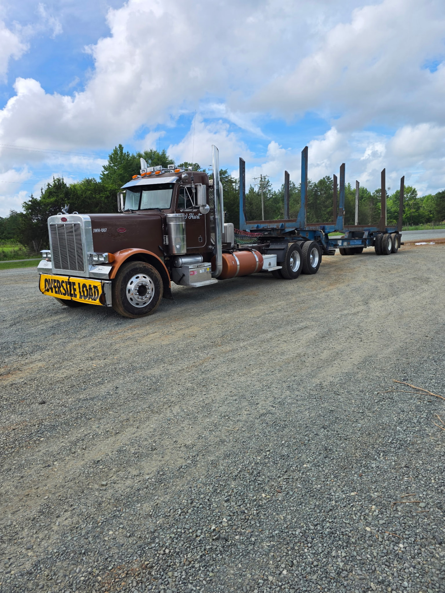 JW Hart Transport JWH-007 brown Peterbilt with empty logging trailer on a gravel lot