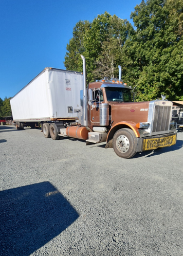 JW Hart Transport brown semi with oversize load banner pulling a long white trailer