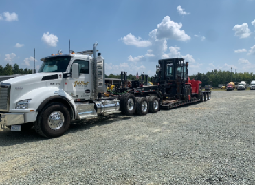White JW Hart Transport semi hauling a forklift and material handler on a lowboy