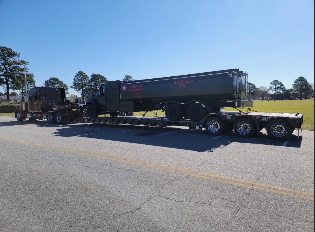 JW Hart Transport semi hauling a black jet fuel tanker trailer on a lowboy