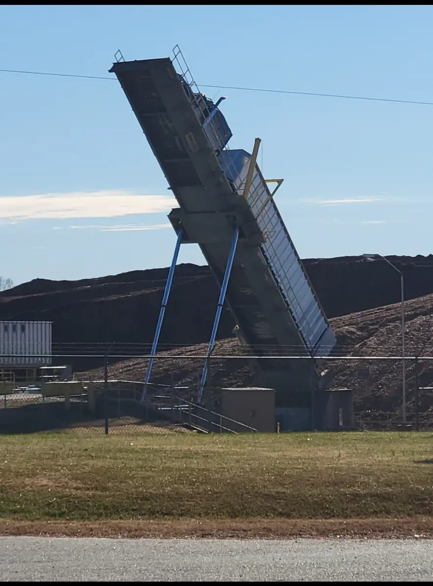 JW Hart Transport dump trailer raised at a steep angle unloading at a material yard