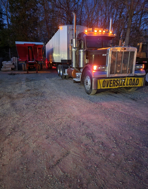 JW Hart Transport truck with oversize load banner and trailer at dusk