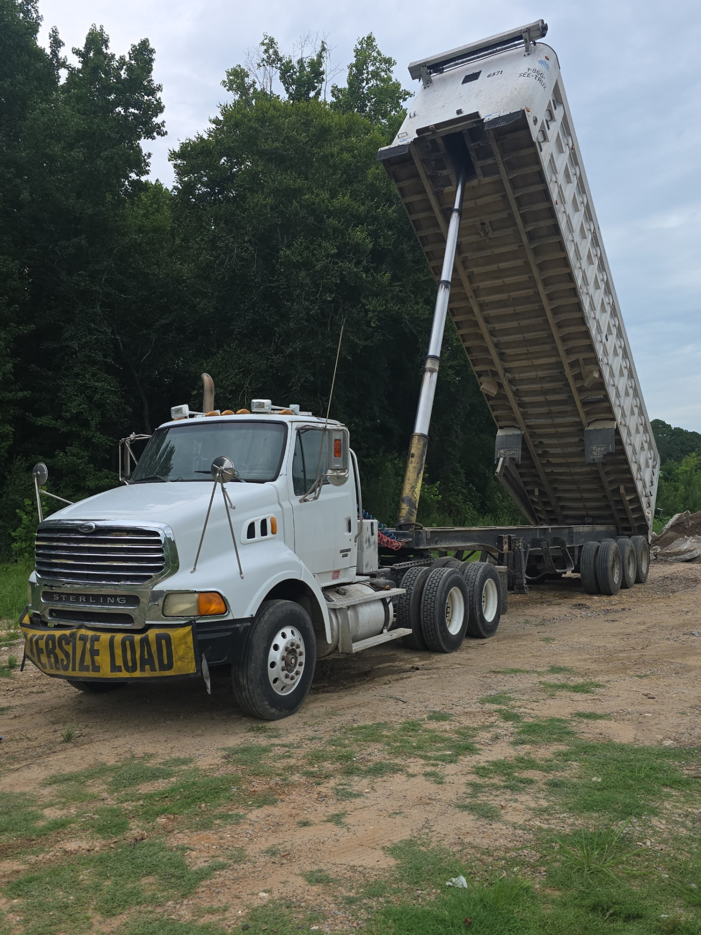 White Sterling dump truck with raised trailer bed at a JW Hart Transport jobsite