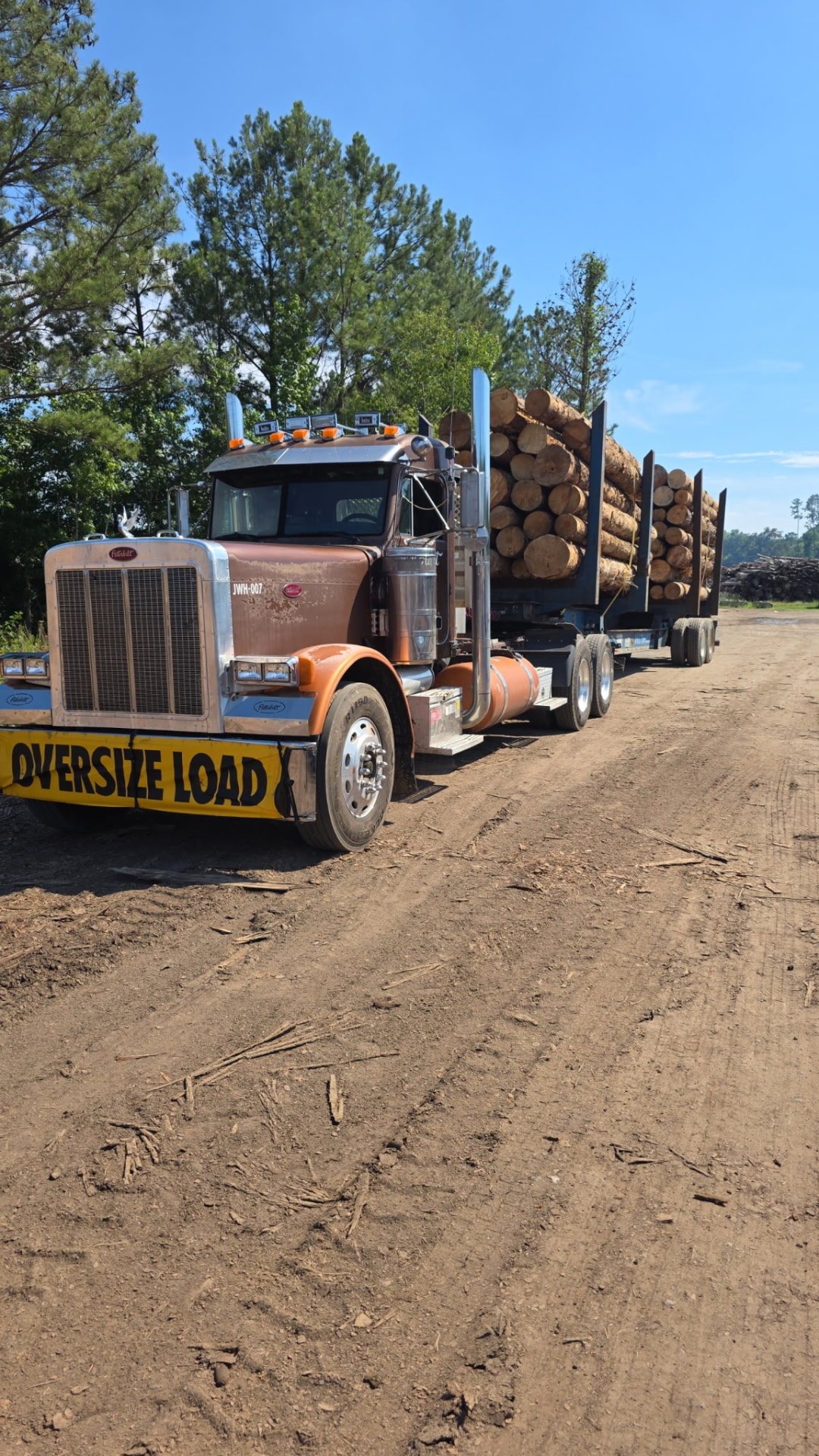 JW Hart Transport JWH-007 hauling a loaded log trailer on a dirt forestry road